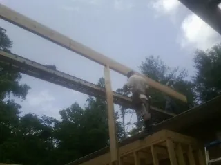 Carpenter setting a ridge beam over a new addition frame — Ice Dam Removal by Roofing Brothers in Alexander City