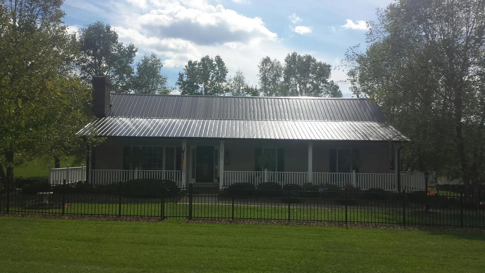 Gray metal roof on a brick ranch with a full width front porch — Gutter Guard Installation work by our crew in Alexander City