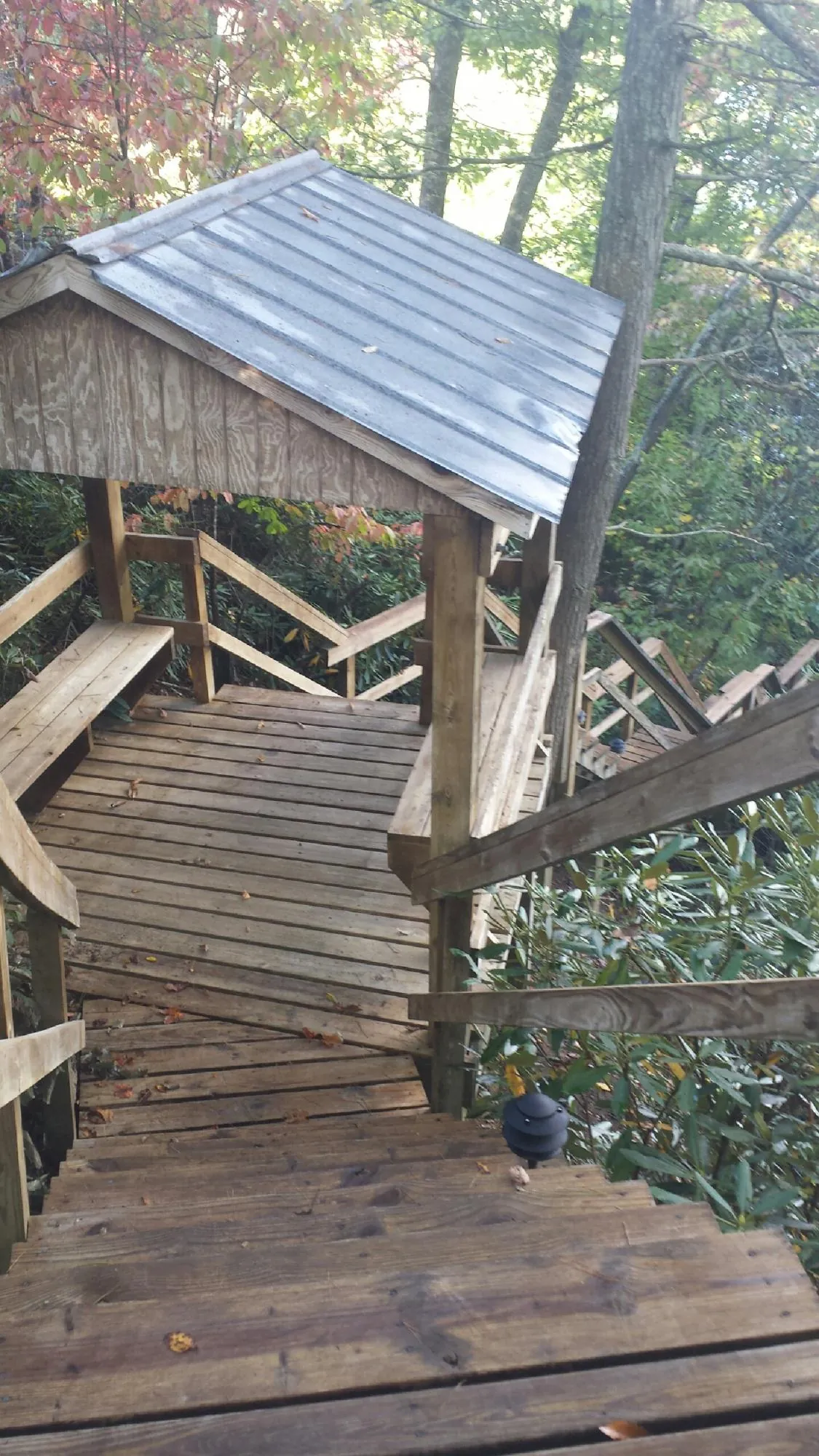Metal roofed shelter over wooden steps on a wooded walkway — Skylight Repair & Installation work by our crew in Alexander City