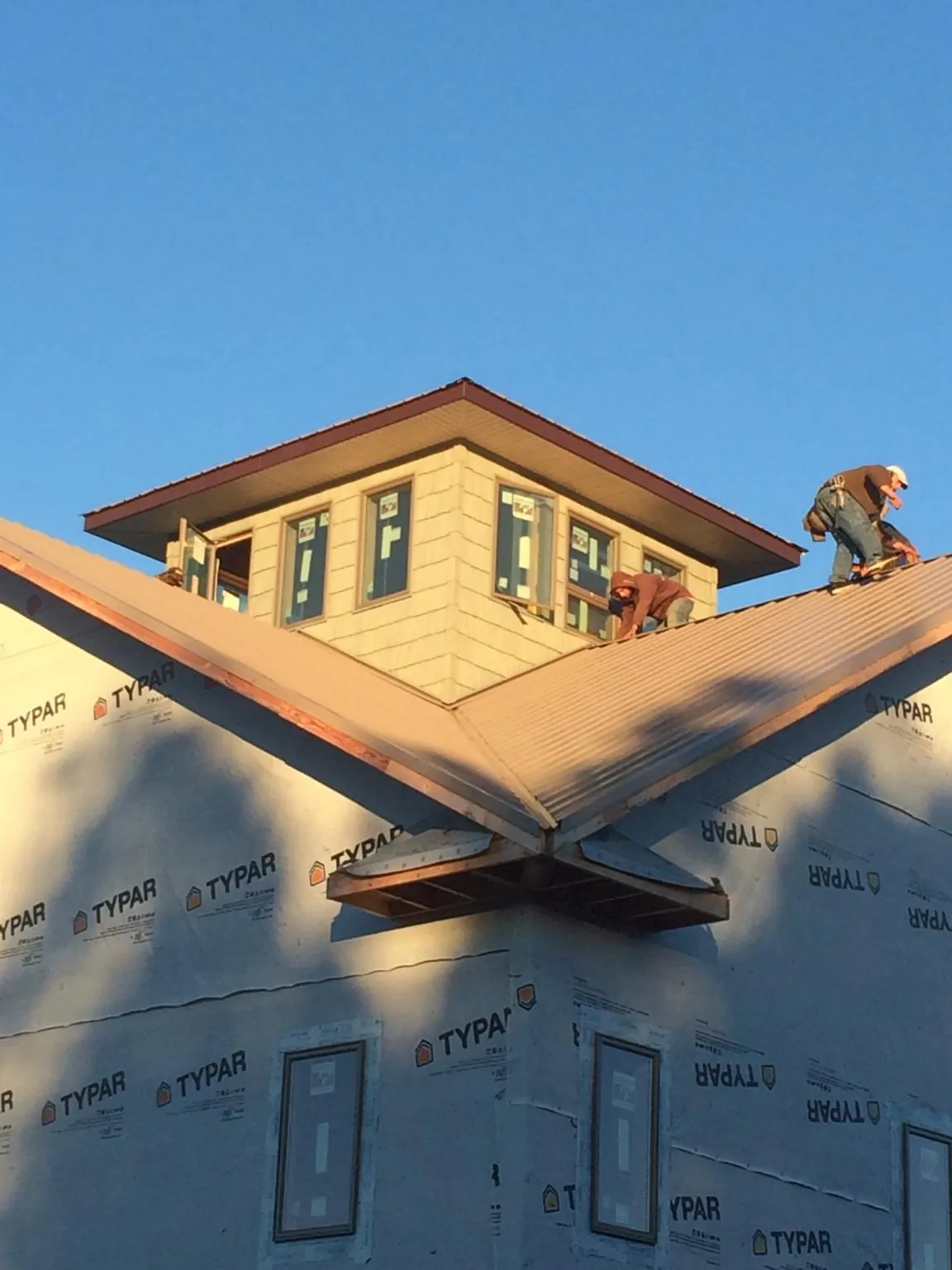 Roofers working around a rooftop cupola on a new metal roof at sunset — Roof Waterproofing in Alexander City by Roofing Brothers
